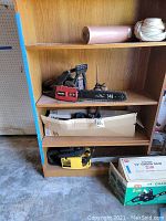 Shelf with Wen 14-inch chainsaw in red housing, Homelite chainsaw yellow/black, and cardboard box, bottom shelf has a McCulloch chainsaw yellow body.