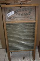 Front view of large wooden washboard showing embossed glass scrubbing board and printed branding on upper wood crossbar