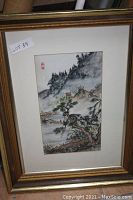 Framed original watercolor painting showing misty mountainous landscape, pine trees, a small house, and water body. Painting has artist signature with red Chinese seal on upper left. Image captured to show art condition and framing.