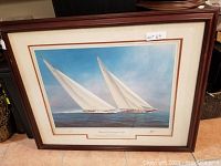 Framed artwork showing two classic J Class yachts racing in open water with full sails. Image captured to show entire framed print and condition.