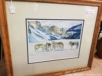 Photo of the entire framed print showing wolves and mountain landscape with the artwork framed in oak wood and a double mat.