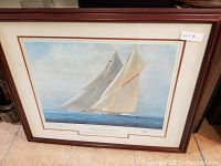 Framed artwork of sailing yachts titled 'Yachts of the America's Cup' showing large sailing boats with white sails on the sea.
