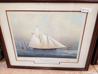 Framed print depicting schooner yacht on water with other vessels in background, titled 'Yachts of the America's Cup'.