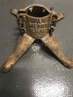 Full view of antique cast iron Christmas tree stand with two legs and embedded screws, showing rust and wear.