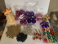 Photo showing a variety of Christmas tree ornaments including ball ornaments in multiple colors, star-shaped ornaments, multiple garlands, and an angel tree topper with lights.