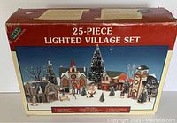 Box showing image of the complete 25-piece lighted village set by Lenmax. Box has some visible damage.