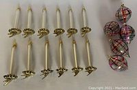 12 frosted glass clip-on candles and 5 plaid glass ornaments arranged side by side