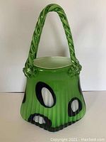 Full view of green glass purse sculpture showing entire body, handle, and pattern
