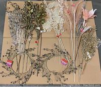 Top view of decorative picks and wreaths laid out on cardboard showing detailed colors and styles including glittered berries and floral branches, some with tags.