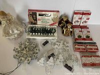 Photo showing all Christmas light strands, vintage angel tree topper, star tree topper, boxed sparkle lights, and battery-operated white metal light strands with ribbons.