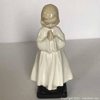 Front view of Royal Doulton Bedtime figurine showing the girl with hands clasped, wearing white nightgown, standing on black base.