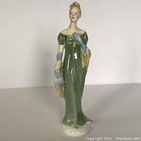 Front view of the Royal Doulton Lorna figurine showing the green dress, blue gloves, yellow shawl, and facial details.