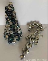 Christmas tree composed of silver, blue, and green bells on wire frame next to candy cane made of brushed silver bells