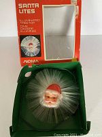 Original NOMA red and green box for Santa tree topper, showing product name and image on box front.