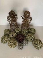 Two brown wicker angel figurines with twelve assorted wicker balls displayed in front