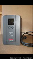 Front view of APC Back-UPS XS 1300 unit showing display screen, buttons, power cable and identification markings.