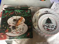 Photo showing both Christmas plates and the central rod stand, plus the original box with design and text in French and English.