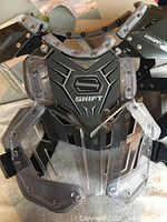 Front view of the black and clear plastic youth chest protector by Shift brand, showing the logo and construction.