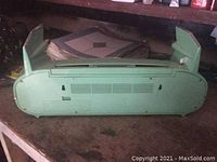 Back view of the classic car radio and tape deck unit showing the green plastic casing and mounting points.