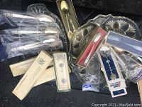 Scope of all spoons shown together in one shot on dark textured background, many in original packaging or protective plastic.