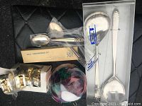 Full view of lot showing spoons, napkin holders, handblown glass ball, and boxed serving spoon set