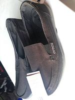 Side view of black canvas Crocs loafer shoes showing the slip-on style and Crocs logo on the side.