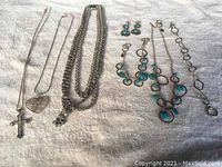 Photo showing various sterling silver jewelry pieces with 925 stamps including necklaces with pendants, a chain bracelet, earrings with turquoise stones.
