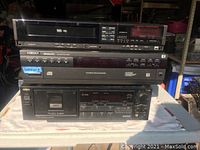 Front view of the stacked AWA stereo components including VHS player top, Kodak CD player middle, and AWA cassette deck bottom.