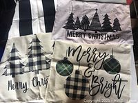 Four pillow covers displayed together showing variety of black and white Christmas themed prints including striped pattern, Christmas trees, and holiday text.