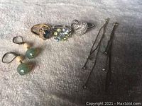 Full lot of three rings and two pairs of earrings on a white fabric background