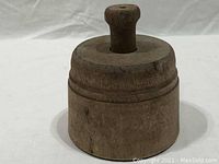 Side view of antique round wood butter mold showing the cylindrical shape and the handle on the lid.