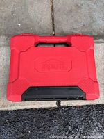 Closed red Jobmate tool case with black latch, showing molded logo.