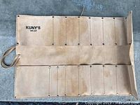 Open leather tool roll showing 17 stitched pockets and brand marking.