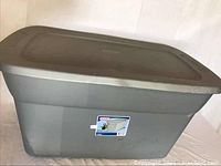 Front side view of grey Sterilite plastic storage container with lid, showing label and overall condition.