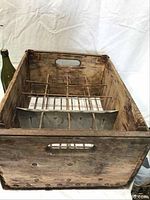 View inside vintage De Laval wooden milk crate showing metal wire bottle dividers and aged wood