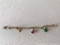 Full view of the sterling silver child's charm bracelet showing all charms attached including a yellow star, red heart, and green frog.