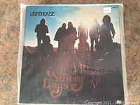 Front cover of Lighthouse's 'Sunny Days' LP in a clear protective sleeve, showing the band silhouetted against a sky with the album title in ornate text.