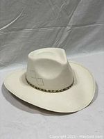 Full view of the white cowboy hat showing the crown shape and gold ornate band.