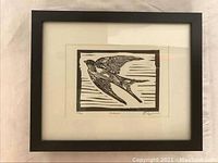 Framed black and white print of a swallow in flight with glass and black frame.