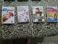 Four Nintendo Wii game cases displayed on a patterned surface with visible titles and cover art.