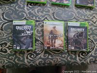 Three Xbox 360 Call of Duty game cases placed side by side on a patterned carpet.