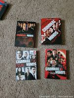 Four DVD sets of Criminal Minds showing the front covers for Seasons 1, 4, 5, and 6 arranged on carpet.