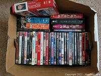 Photo of a cardboard box filled with assorted DVDs including Everybody Loves Raymond, The OC, The Dark Knight, and others.