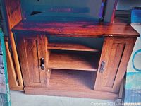 Wooden TV stand showing front view with two closed cabinet doors on both sides and open shelving in the middle.