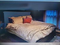 Photo of king size bed assembled with headboard, footboard, mattress, and bedding including pillows and blanket.