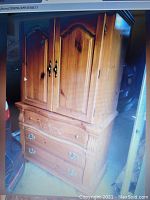 Full view of the large wooden cabinet showing the upper cupboard section with two doors and lower section with three drawers and decorative hardware.