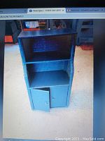 Front view of blue wicker storage cabinet showing two open shelves and one small door at bottom.