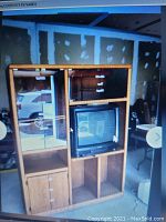Two piece wooden entertainment center with glass display shelves, storage cabinets, and open space for TV.