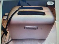 Photo of silver DeLonghi toaster with two bread slots, black side dial, and power cord visible.