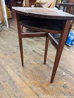 Side view of the solid oak corner telephone stand showing the tapered legs and cubby slot beneath the top surface.